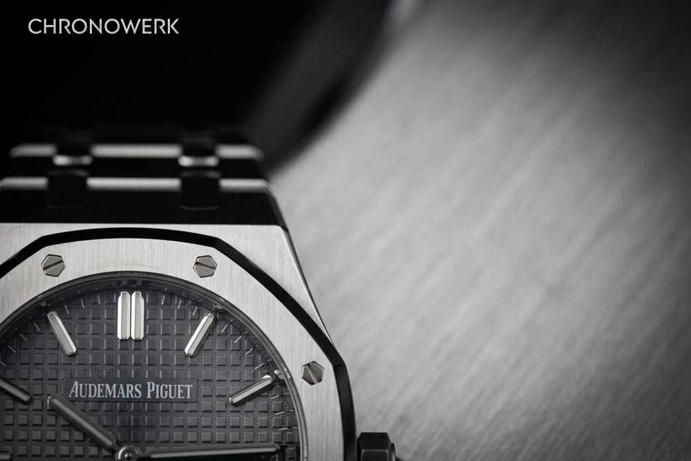Ausschnitt einer Stahl-Sportuhr mit achteckiger Schraubenlünette und grauem Tapisserie-Zifferblatt mit Signatur Audemars Piguet