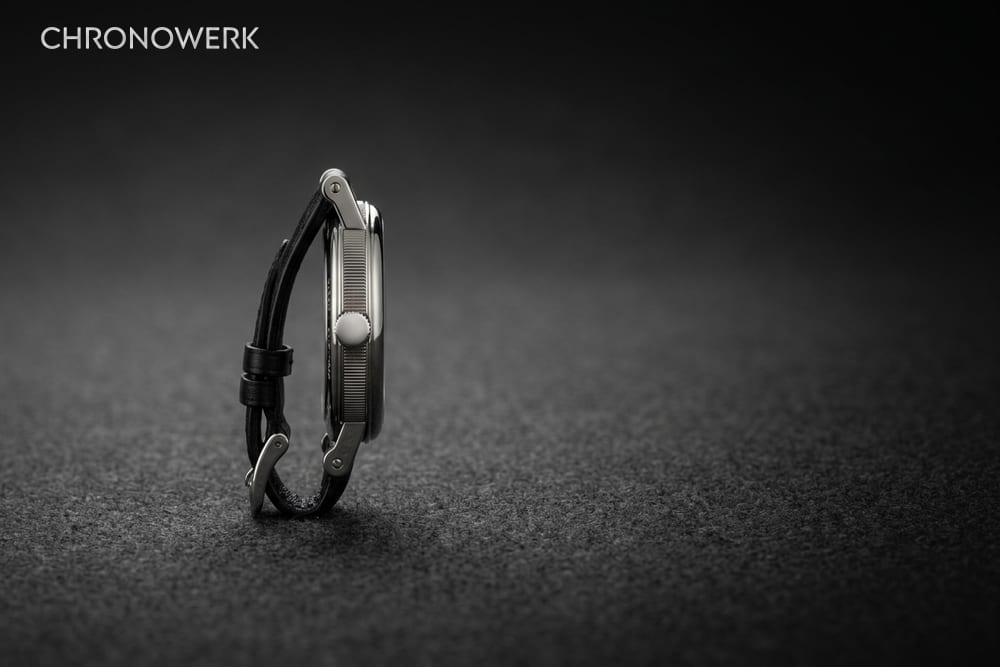Seitenansicht eines Uhrengehäuses mit kannelierter Flanke und schwarzem Lederband im linken Bilddrittel